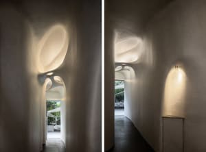 A minimalist interior space featuring modern materials with curved walls and light fixtures.