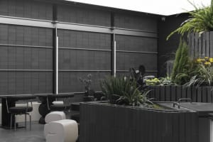 Modern urban lounge area with concrete walls, white furniture, and green plants.