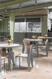 Modern cafe interior with wooden tables, metal chairs, and minimalistic design.