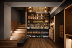 A modern bar interior with wooden shelves displaying a variety of bottles.