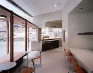 A sleek, minimalist coffee shop designed with concrete and wood materials, featuring a contemporary interior layout.