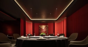 A luxurious private dining room with red leather seating and a circular dining table.