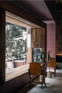 Indoor bar area with reclaimed wood furniture, plants, and industrial design elements.