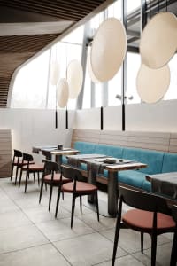 A modern cafe with a sleek design featuring minimalist furniture, concrete tiles, and large windows for natural light.