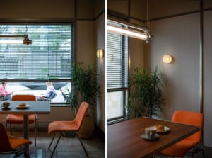 A cozy cafe interior featuring metal, wood, and fabric materials under warm lighting and potted plants by the window.