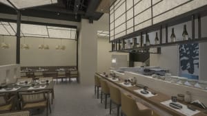 A modern restaurant interior featuring wooden tables, glass windows, and textured fabric seating