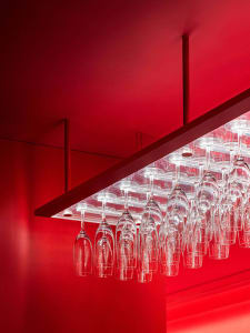 A modern minimalist bar counter with clear glass hanging shelves.
