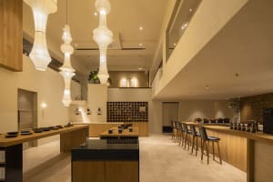 A modern minimalist restaurant interior with wood elements and a high, open ceiling.