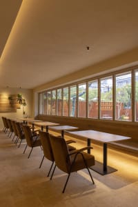 Modern restaurant interior with tables, chairs, and large windows.