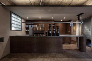 An industrial-style coffee shop counter with concrete walls and a tiled bar.