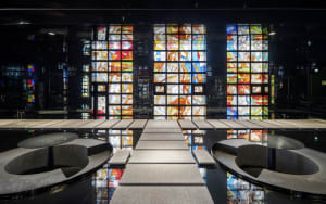 A spacious church interior with concrete flooring and vibrant stained-glass windows.