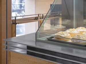 A metal and glass display counter showcasing baked goods in a cafe.