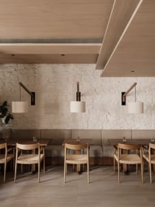 A photograph of a modern restaurant interior with wooden furniture and stone walls.