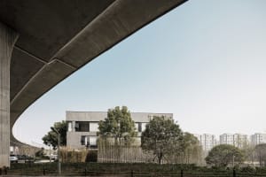 Modern office building with concrete facade and greenery in the foreground.