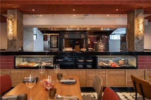 A modern restaurant interior featuring wooden tables, concrete pillars, and glass displays.