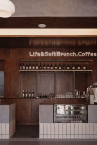 Modern coffee shop interior showcasing an elegant wooden counter with bottles of wine lined up on the shelf.