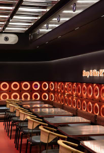 Modern industrial restaurant interior with metal tables, leather seats, and circular light fixtures