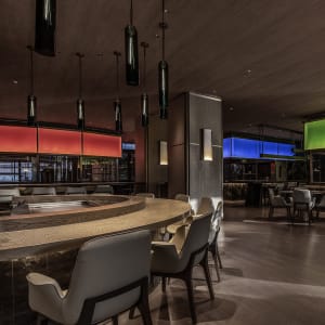 A modern restaurant's interior with wooden tables, glass lighting fixtures, and metallic hardware.