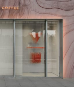 Modern retail storefront featuring glass doors and wall with abstract shapes and neon signage.