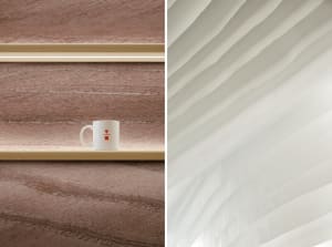 A minimalist wooden shelf displaying a white ceramic mug with a red design against a textured brown wall.