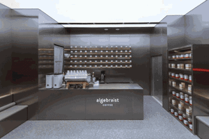 A minimalist coffee shop interior with a metal counter and shelves.