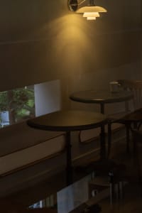 A minimalist cafe interior featuring metal tables under warm lighting.
