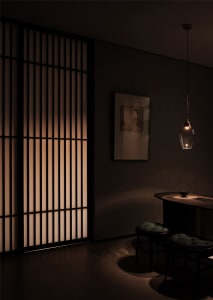 A minimalist restaurant interior with dark lighting and wooden materials.