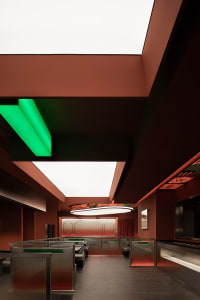 A modern, sleek restaurant with metallic frames and green and red lighting.