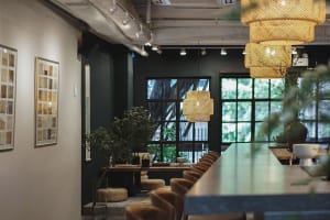An industrial-style interior with wooden elements, featuring long tables, chairs, and decorative hanging lights.