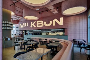 Contemporary minimalist restaurant interior featuring pink concrete walls and pink tiled floors.