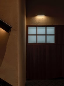 A dark wood panelled entrance with frosted glass panels, illuminated by a warm light fixture above.