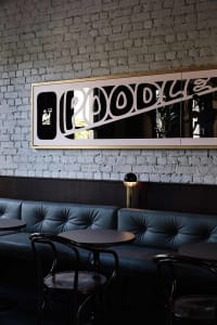 Industrial style restaurant interior with metal sign, leather seating, and brick wall