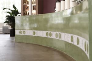 A minimalist interior with an organic green concrete wall.