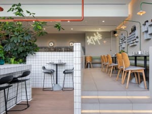 A modern cafe interior featuring concrete tiled walls and wooden furniture.