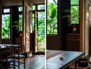 Interior of a modern restaurant featuring wooden tables, glass windows, and textured concrete walls.
