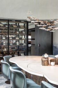Modern interior design featuring a circular dining table with concrete legs and blue leather chairs, illuminated by contempor