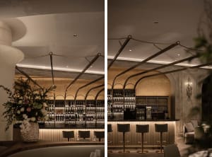 A modern restaurant bar interior with metallic stairs and gold-colored lighting.