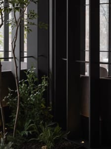 Modern, industrial-style restaurant interior with metal walls and green plants.