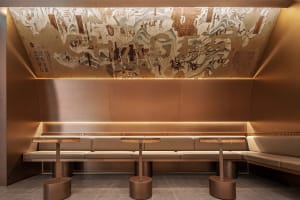 Café interior with retail-style layout, modern leather seating, and large mural on the ceiling.