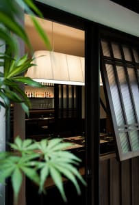A modern restaurant interior with dark wood elements, glass windows, and fabric lighting.