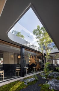 Modern restaurant interior featuring glass walls and concrete elements.