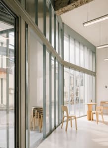 A modern cafe interior with large windows and wooden furniture.