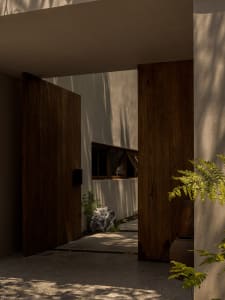 A modern residential entrance featuring wooden doors and concrete flooring.