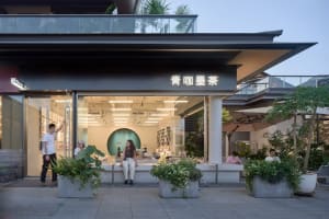 Outdoor seating area of a modern coffee shop with concrete planters and glass storefront.
