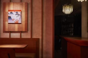Industrial-style restaurant interior with wooden paneling, abstract art, and crystal chandelier.