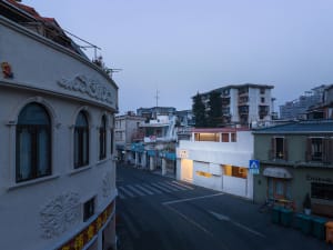 An evening view of an urban street with buildings and storefronts.