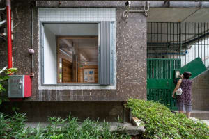 A minimalist entranceway featuring a tile wall and a green metal gate.