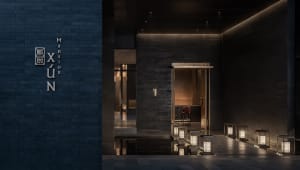 A modern restaurant entryway featuring dark brick walls with a minimalist design.