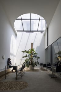 A modern office lounge featuring concrete, glass, and wood materials.