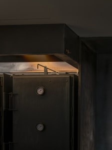A close-up of an industrial-style kitchen with a metallic door featuring gauges.